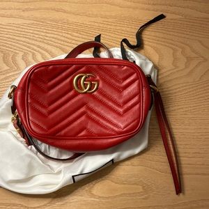 Red leather Gucci camera bag with gold metal details.